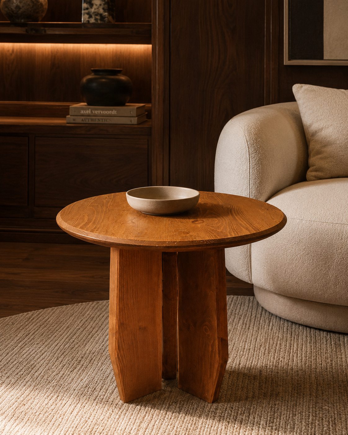 Round solid wood side table beside a sofa with warm hand-finished wood grain.